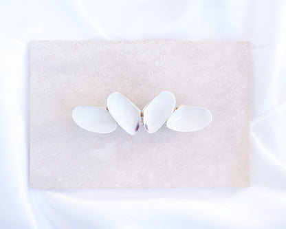 Butterfly-shaped hair clip on a beige stone background. White Coquina Shells Butterfly Hair Clip Barrette on light stone displayed. Handpicked Real Coquina Shells. The shells are white in color and attached on the hair clip like a butterfly. The model has brown long hair. Sea Butterfly Shell Hair Decoration, Seashell Wedding Hair accessories, Coastal Christmas gift, Beach Wedding Hair