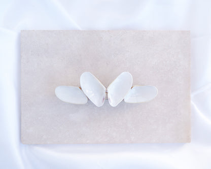 White Coquina Shells Butterfly Hair Barrette on light stone displayed. Handpicked Real Coquina Shells. The shells are white in color and attached on the hair clip like a butterfly. The model has brown long hair. Sea Butterfly Shell Hair Decoration, Seashell Wedding Hair accessories, Coastal Christmas gift, Beach Wedding Hair