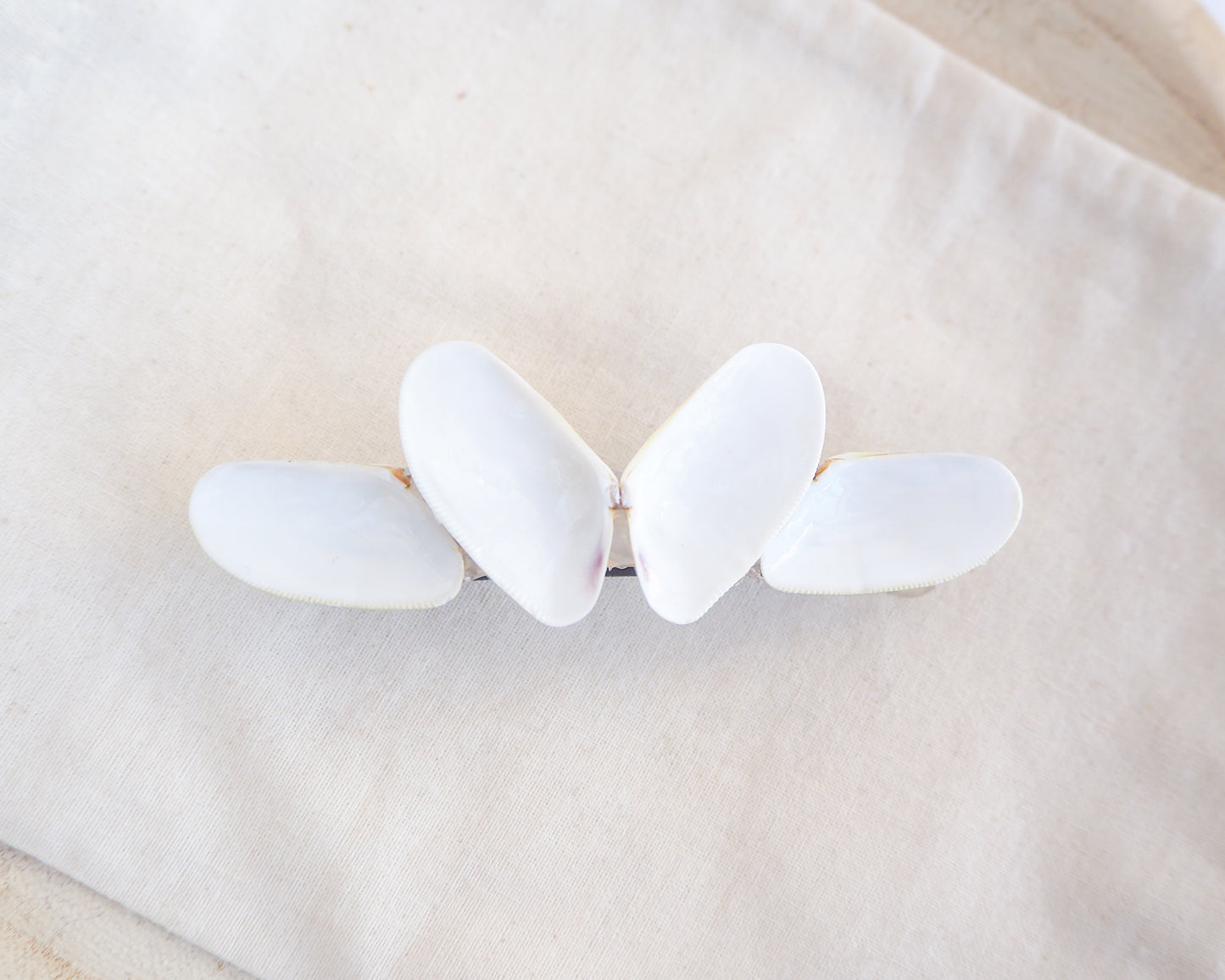 White butterfly-shaped hair clip on a beige fabric background. Handpicked Real Coquina Shells. The shells are white in color and attached on the hair clip like a butterfly. The model has brown long hair. Sea Butterfly Shell Hair Decoration, Seashell Wedding Hair accessories, Coastal Christmas gift, Beach Wedding Hair