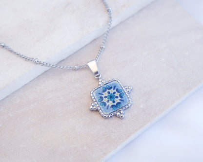 Close up of Blue Turquoise Portuguese Tile Square Necklaces Silver on stone displayed. Made with Silver stainless steel and white blue mosaic pendant inspired by the Portuguese Azulejo design pattern. 