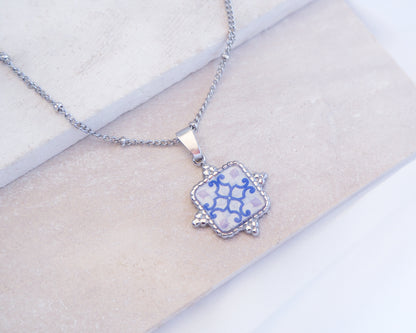 Close up of White Blue Portuguese Tile Square Necklaces Silver on stone displayed. Made with Silver stainless steel and white blue mosaic pendant inspired by the Portuguese Azulejo design pattern. 