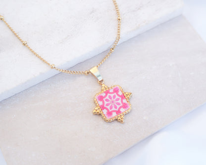 Close up of Pink Portuguese Tile Square Necklaces Gold on stone displayed. Made with 18k gold stainless steel and white pink mosaic pendant inspired by the Portuguese Azulejo design pattern. 