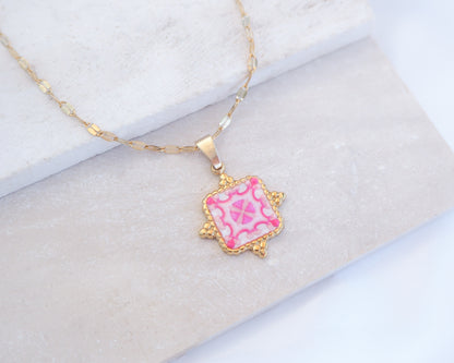 Close up of Pink White Portuguese Tile Square Necklaces Gold on stone displayed. Made with 18k gold stainless steel and white pink mosaic pendant inspired by the Portuguese Azulejo design pattern. 