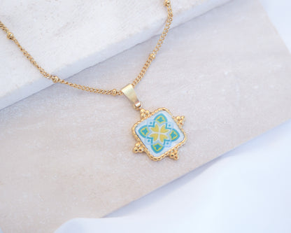 Close up of Green Yellow Portuguese Tile Square Necklaces Gold on stone displayed. Made with 18k gold stainless steel and white green yellow mosaic pendant inspired by the Portuguese Azulejo design pattern. 