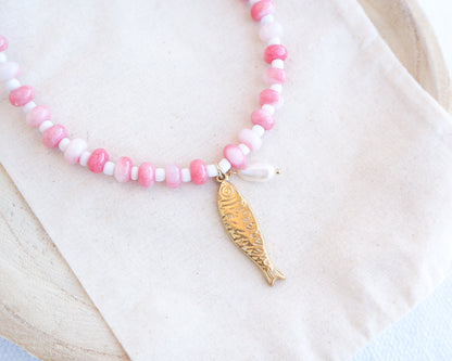 Necklace with pink and white beads and a gold sardine fish pendant and freshwater pearl bead on a person wearing a white top. The necklace is made with seed beads and freshwater pearls and a big gold sardine fish The sardine fish pendant is made of 18k gold stainless steel. 