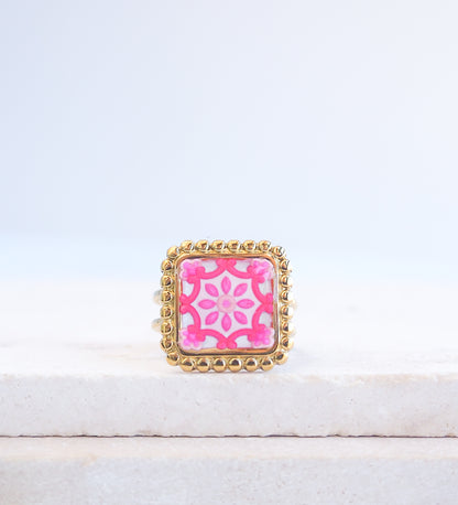Pink Portuguese Tile Square Ring on stone displayed. Rings is handmade with 18k gold stainless steel and has a pink white floral tile pattern inspired by the Portuguese azulejos tiles. 