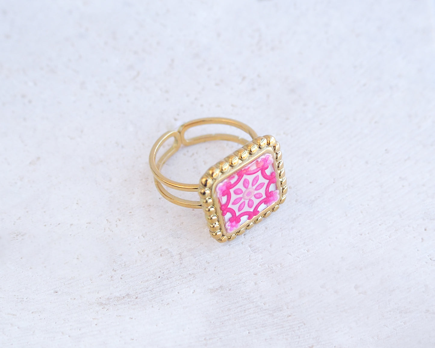 Side view of Pink Portuguese Tile Square Ring on stone displayed. Rings is handmade with 18k gold stainless steel and has a pink white floral tile pattern inspired by the Portuguese azulejos tiles. 