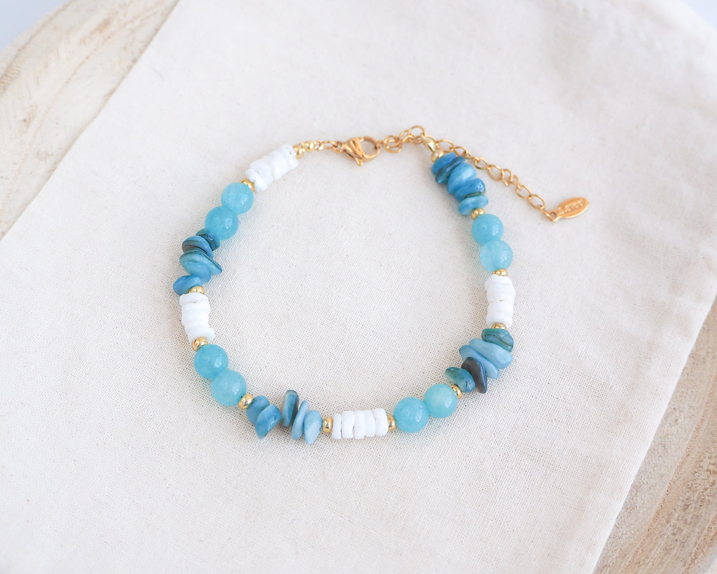 Beaded bracelet with blue and white beads on a light background. Made with white shell beads, turquoise stones and aquamarine gemstone beads. The color is turquoise combined with white. 