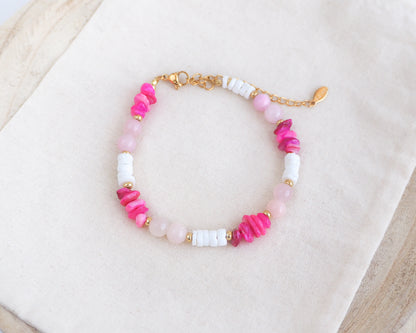 Beaded bracelet with pink, white, and gold beads on a light background. Made with rose quartz, pink stones, white shell beads. The color is pink combined with white. 