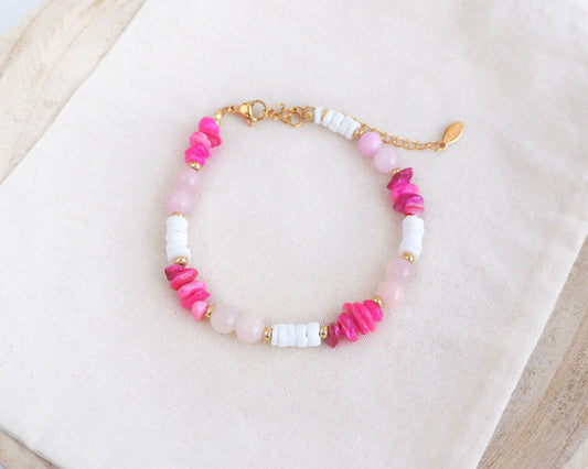 Beaded bracelet with pink, white, and gold beads on a light background. Made with rose quartz, pink stones, white shell beads. The color is pink combined with white. 