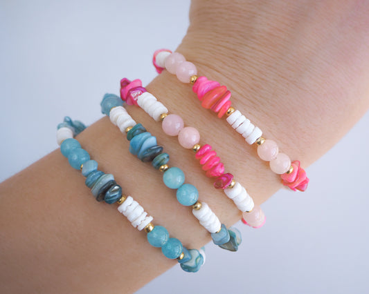 Colorful beaded bracelets on a wrist against a light background. Model wearing seaside bracelets on wrist. Made with rose quartz, pink stones, white shell beads, turquoise stones and aquamarine gemstone beads. The color is pink and turquoise combined with white. 