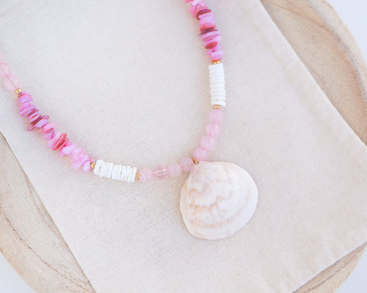 Big clam necklace with pink and white beads and a shell pendant on display. Shell is paired with rose quartz gemstone beads, soft pink stones and white shell beads. The shell is a Norwegian cockle shell handpicked from Portugal and is about 4 cm. The color of the shell is ivory white with a beige brown pattern.