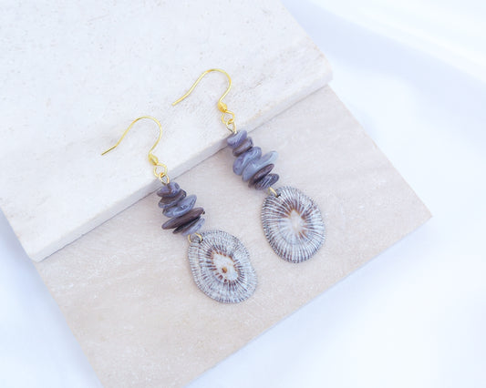 Gold hoop earring with shell and dark stones on display. Gold Striped Limpet Shell Dark Grey Stone Drop Earrings. Gold hoops with real shells from Portugal. Made with 14k gold stainless steel hoop earrings.   
