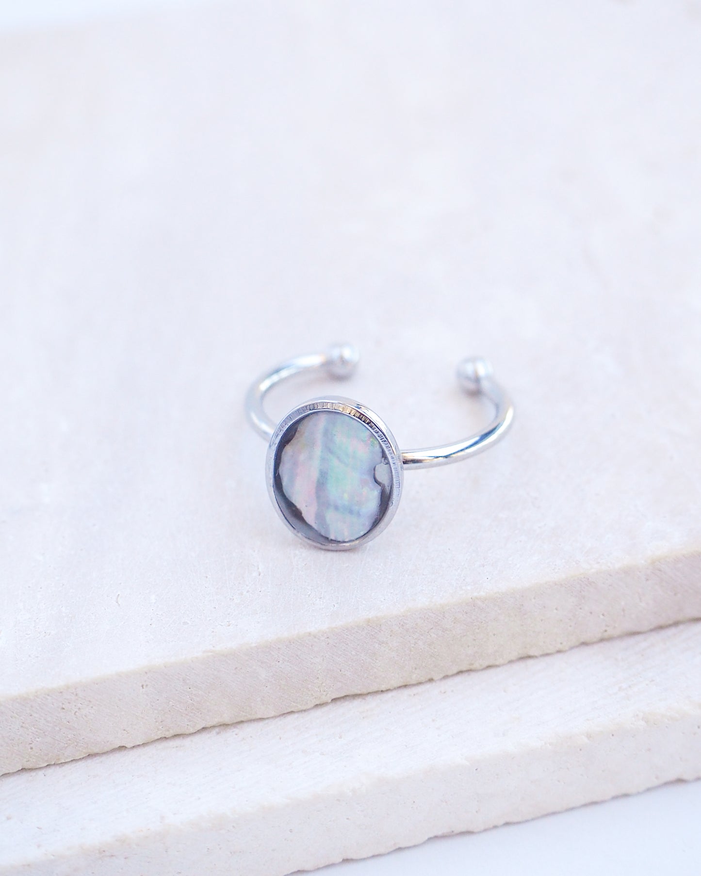 Close up of Silver ring with a piece of abalone shell on stone displayed. The piece of abalone shell was found on the beaches of Portugal. Set in a bezel ring made of silver stainless steel. The ring is adjustable. 