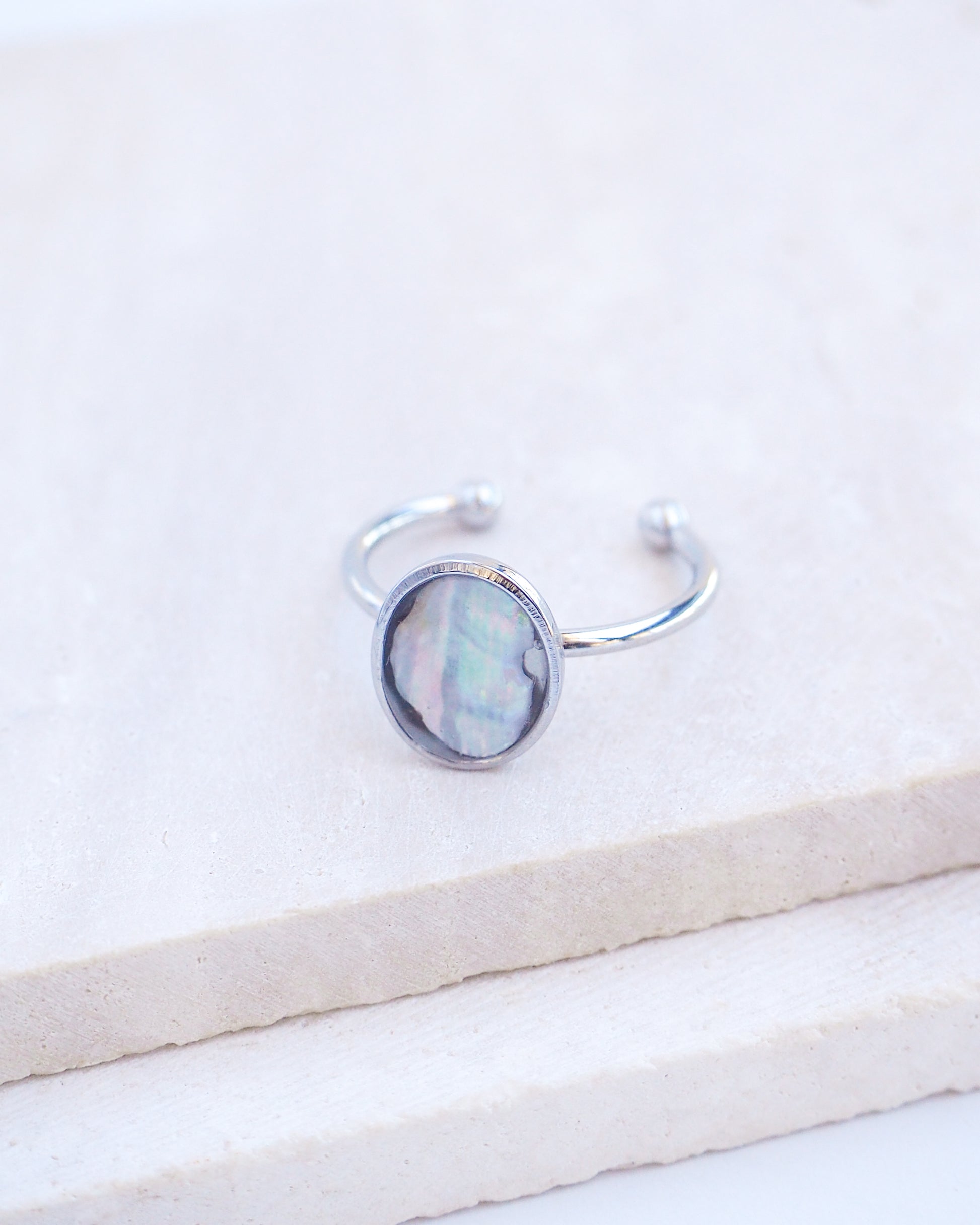 Close up of Silver ring with a piece of abalone shell on stone displayed. The piece of abalone shell was found on the beaches of Portugal. Set in a bezel ring made of silver stainless steel. The ring is adjustable. 