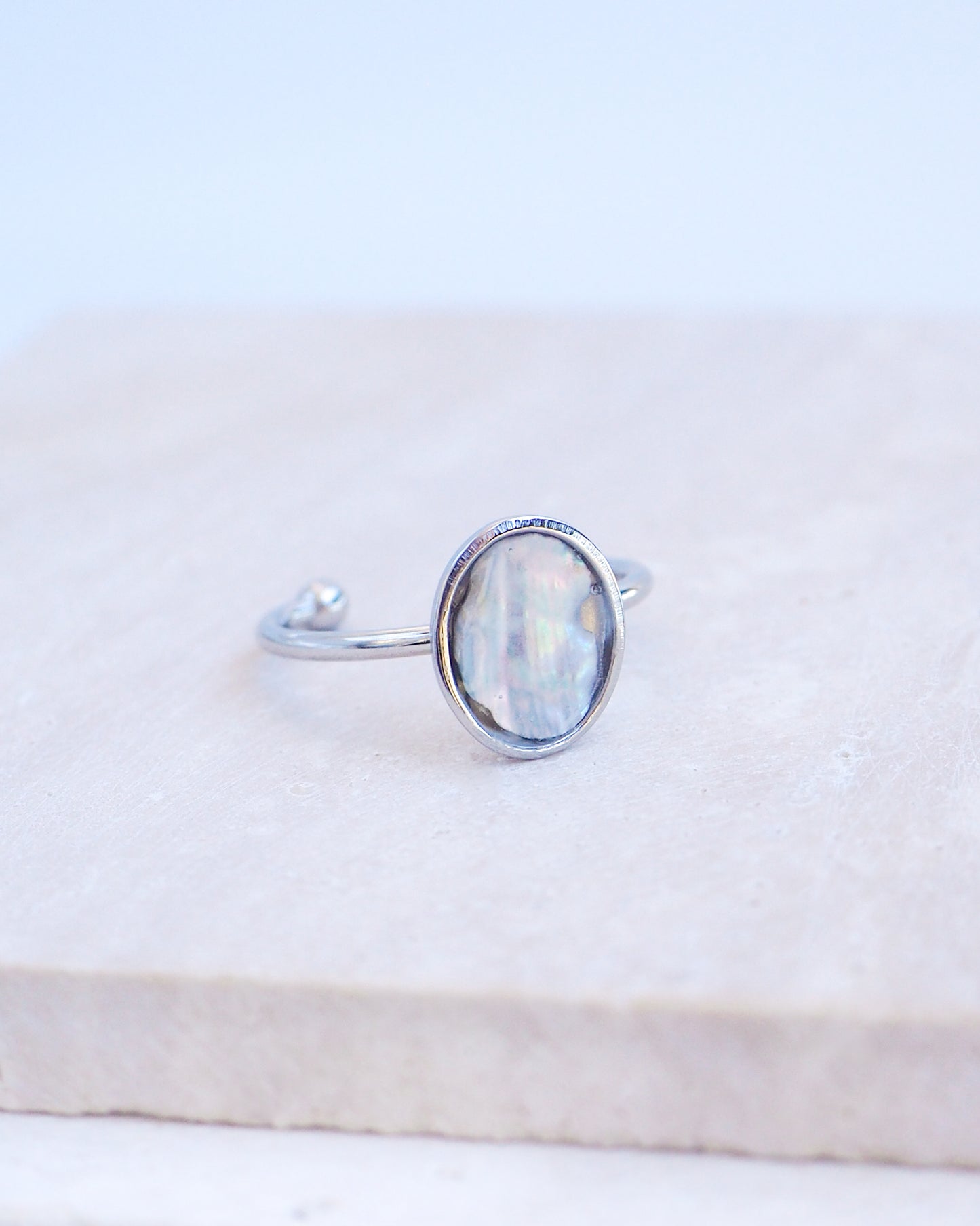 Side view of Silver ring with a piece of abalone shell on stone displayed. The piece of abalone shell was found on the beaches of Portugal. Set in a bezel ring made of silver stainless steel. The ring is adjustable. 