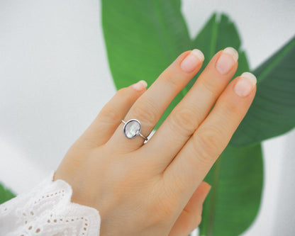 Model wearing a silver ring with a piece of abalone shell. The piece of abalone shell was found on the beaches of Portugal. Set in a bezel ring made of silver stainless steel. The ring is adjustable. 