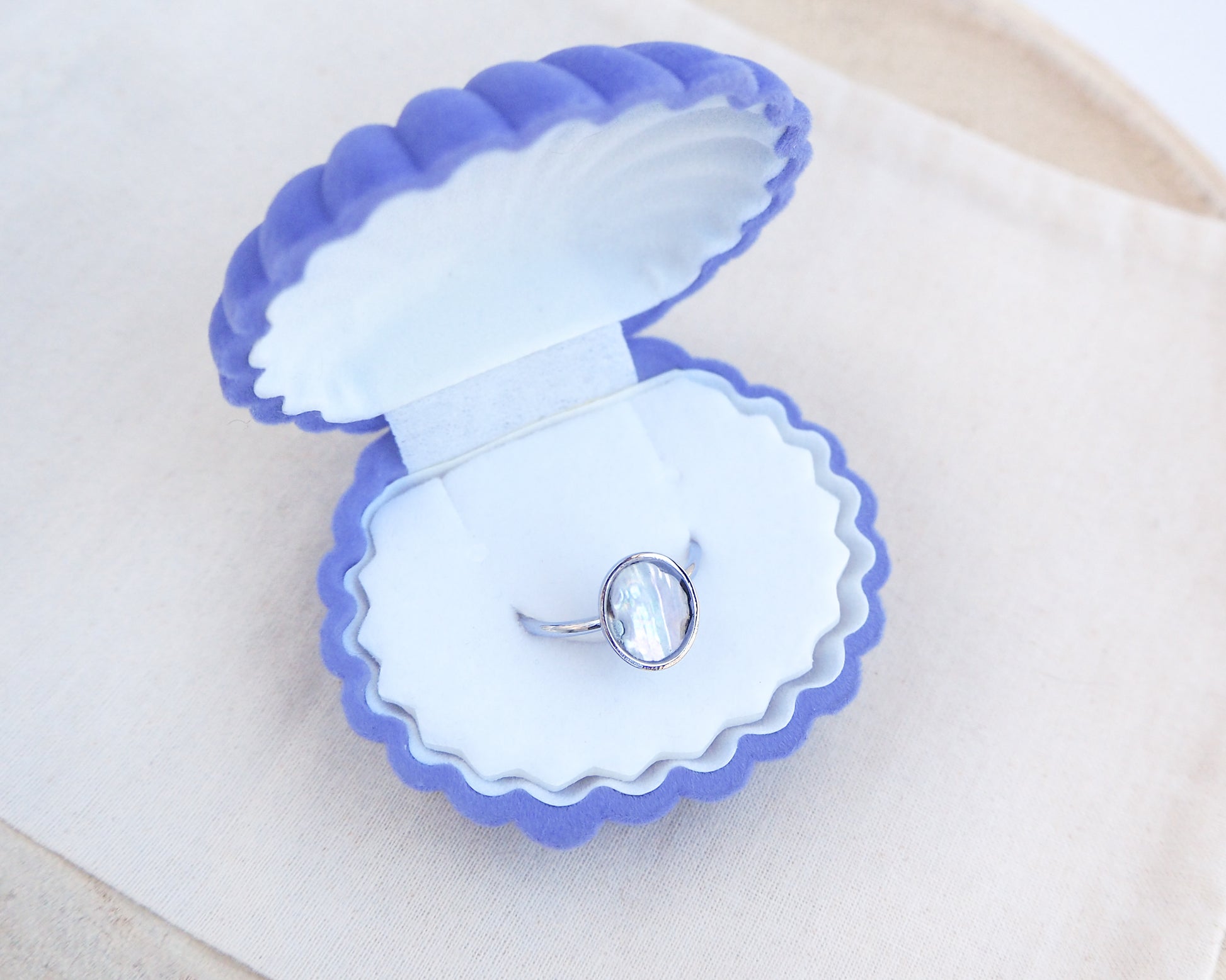 Silver ring with a piece of abalone shell in blue velvet seashell jewelry box. The piece of abalone shell was found on the beaches of Portugal. Set in a bezel ring made of silver stainless steel. The ring is adjustable. 