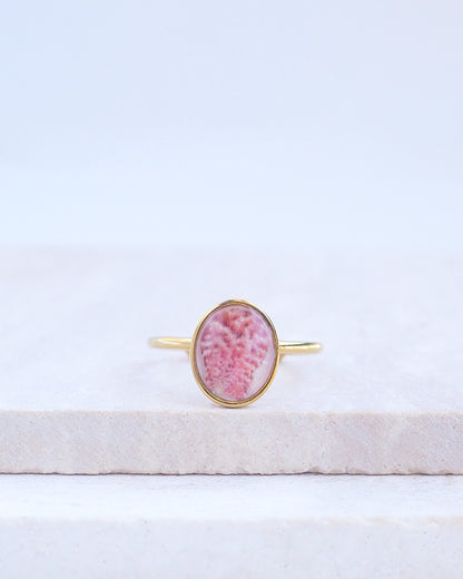 Ring with a pink and gold design on a white fabric background. Tiny Scallop Shell Gold Ring on stone displayed. Tiny Pink Scallop Shell Bezel Ring, 18k gold stainless steel, handpicked scallop shell from the beach of Portugal.
