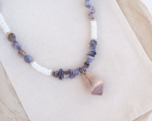 Necklace with grey and white beads and a large cone shell pendant on a light background. A necklace with a mediterranean cone shell paired with Botswana agate gemstone beads and white shell beads. The shell is a mediterranean cone shell from Portugal and is about 3,5 cm. The color of the shell is brown.