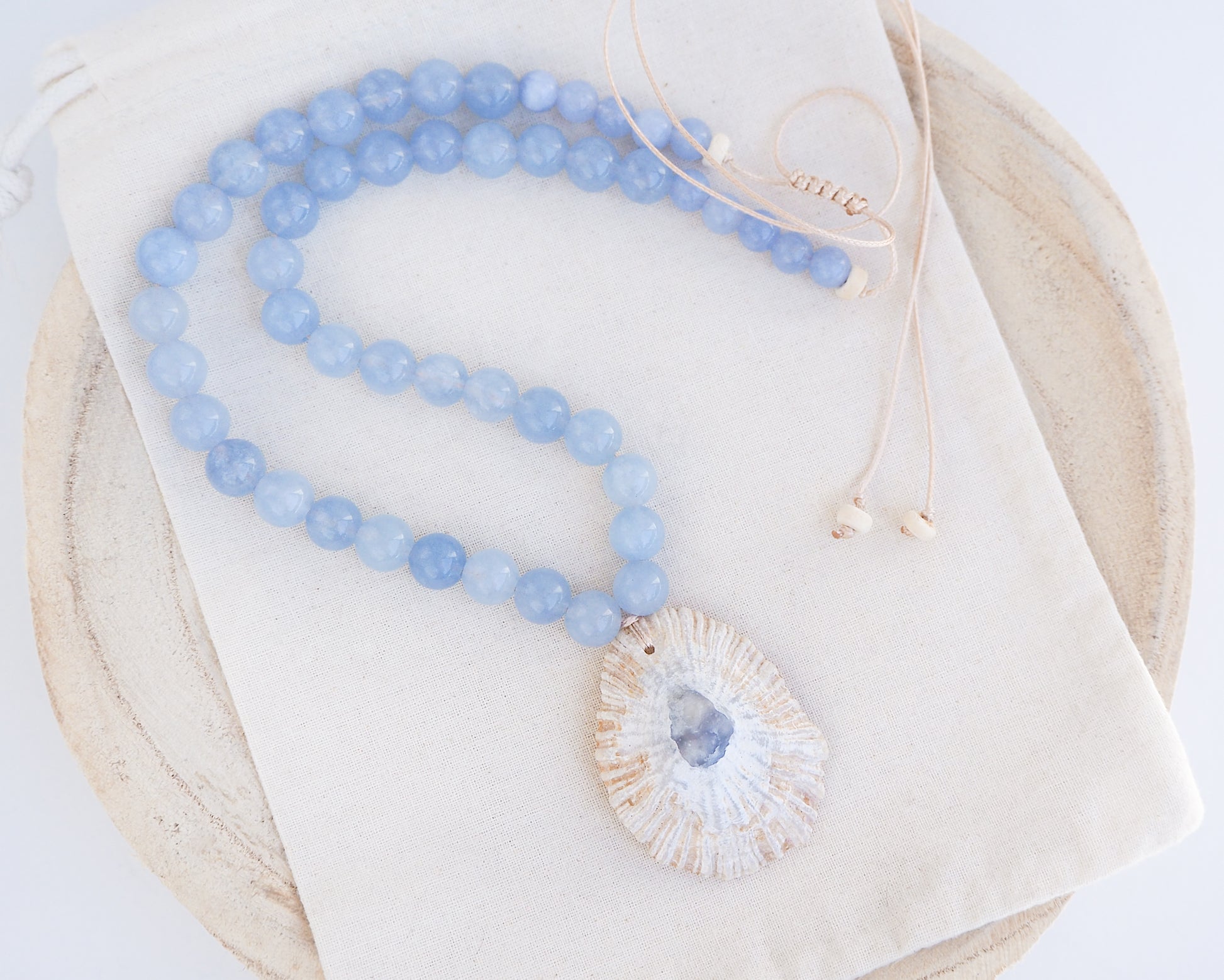 Big Limpet shell paired with aquamarine gemstone beads on display. The shell is a Mediterranean Limpet shell from Portugal and is about 5 cm. The color of the shell is ivory beige with a grey blue center
