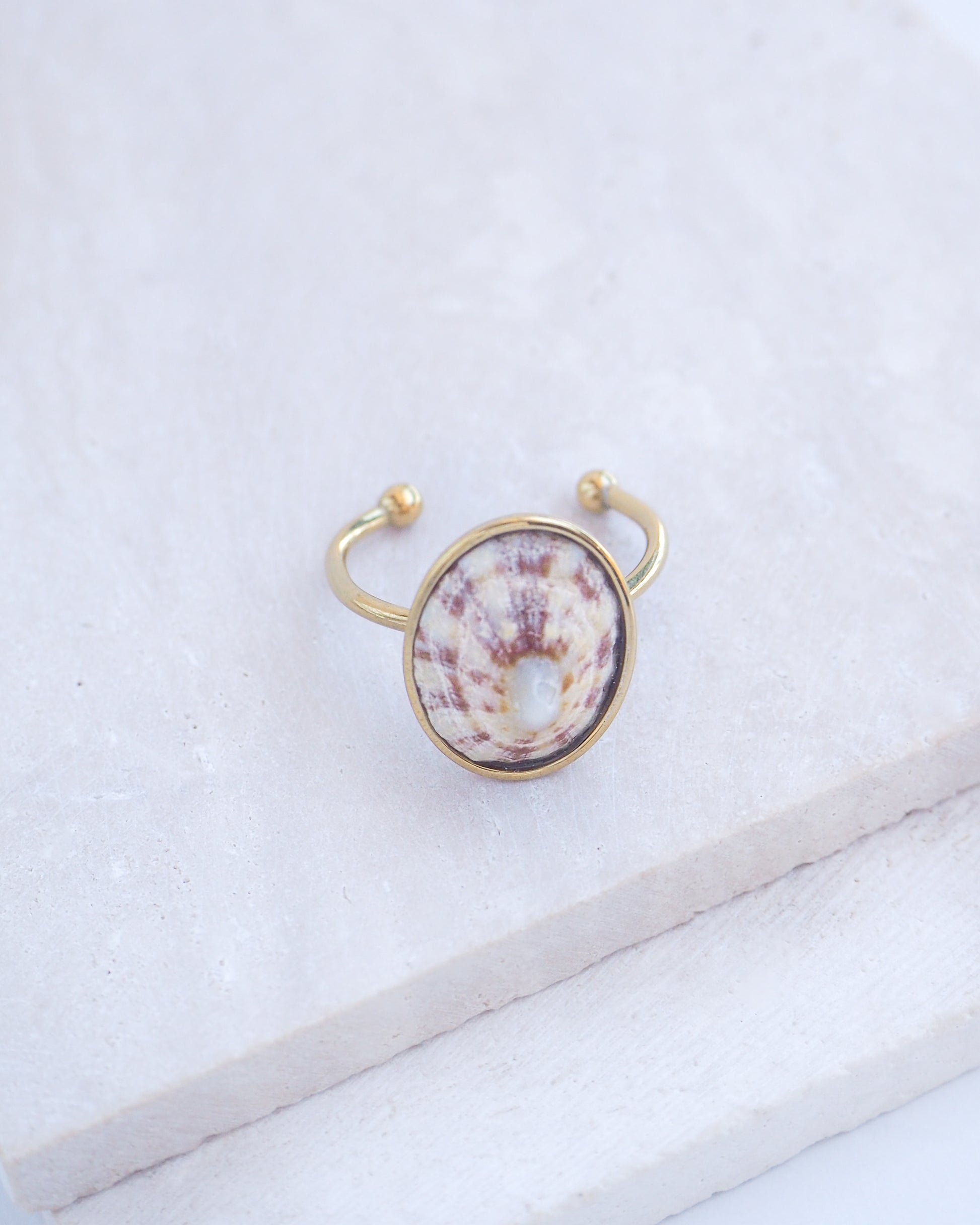 Side view of Light Limpet Shell Bezel Ring on display. Made with a handpicked Rough Limpet Limpet Shell from Portugal set in a 18k gold stainless steel bezel. It's an adjustable ring 