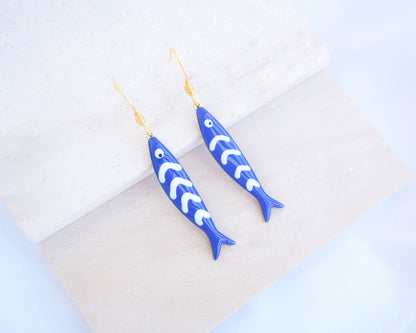 Dark Blue Sardine Fish Earrings with 14k gold stainless steel earring hooks displayed on stone, Beautiful gift for Portugal lovers or holiday memory, coastal jewelry from Portugal
