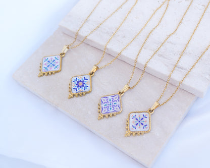 Side view of 4 gold Portuguese Tile Necklace Floral Garden on stone displayed. Made with gold stainless steel and the colorful floral pendant are inspired by the Portuguese Azulejo design pattern. 