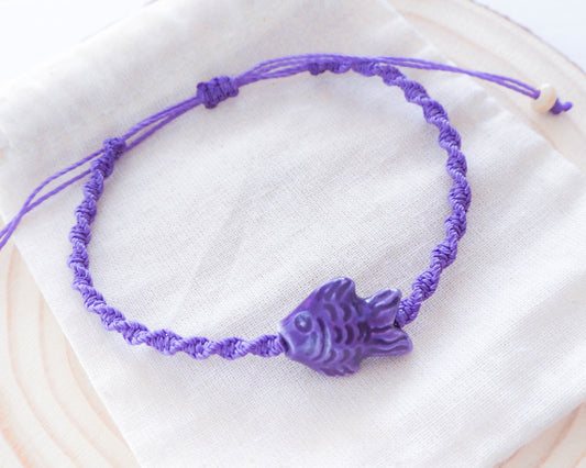 A close-up photo of the Fish Bracelet's intricate ceramic fish charm with vibrant purple enamel detailing