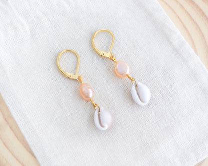 Gold Tiny Cowrie Seashell Pearl Earrings on display. 18k gold stainless steel cowrie pearl earrings handpicked from Portugal