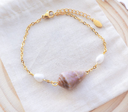 Seaside Sophistication: Close-up of Gold Cone Shell and Freshwater Pearl Bracelet on Gold Chain