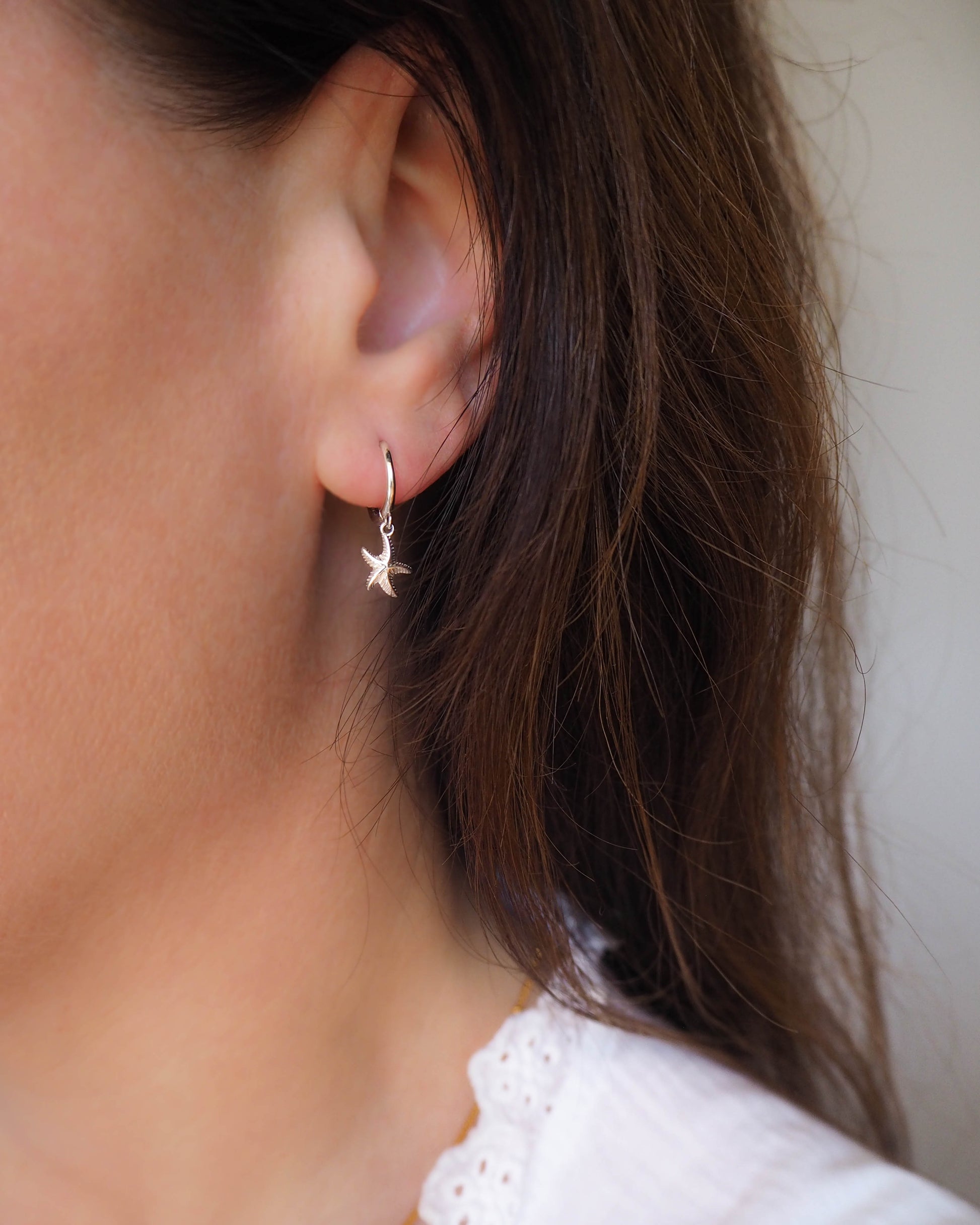 Close-up of a person wearing a star-shaped earring with a neutral background