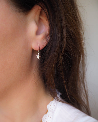 Close-up of a person wearing a star-shaped earring with a neutral background