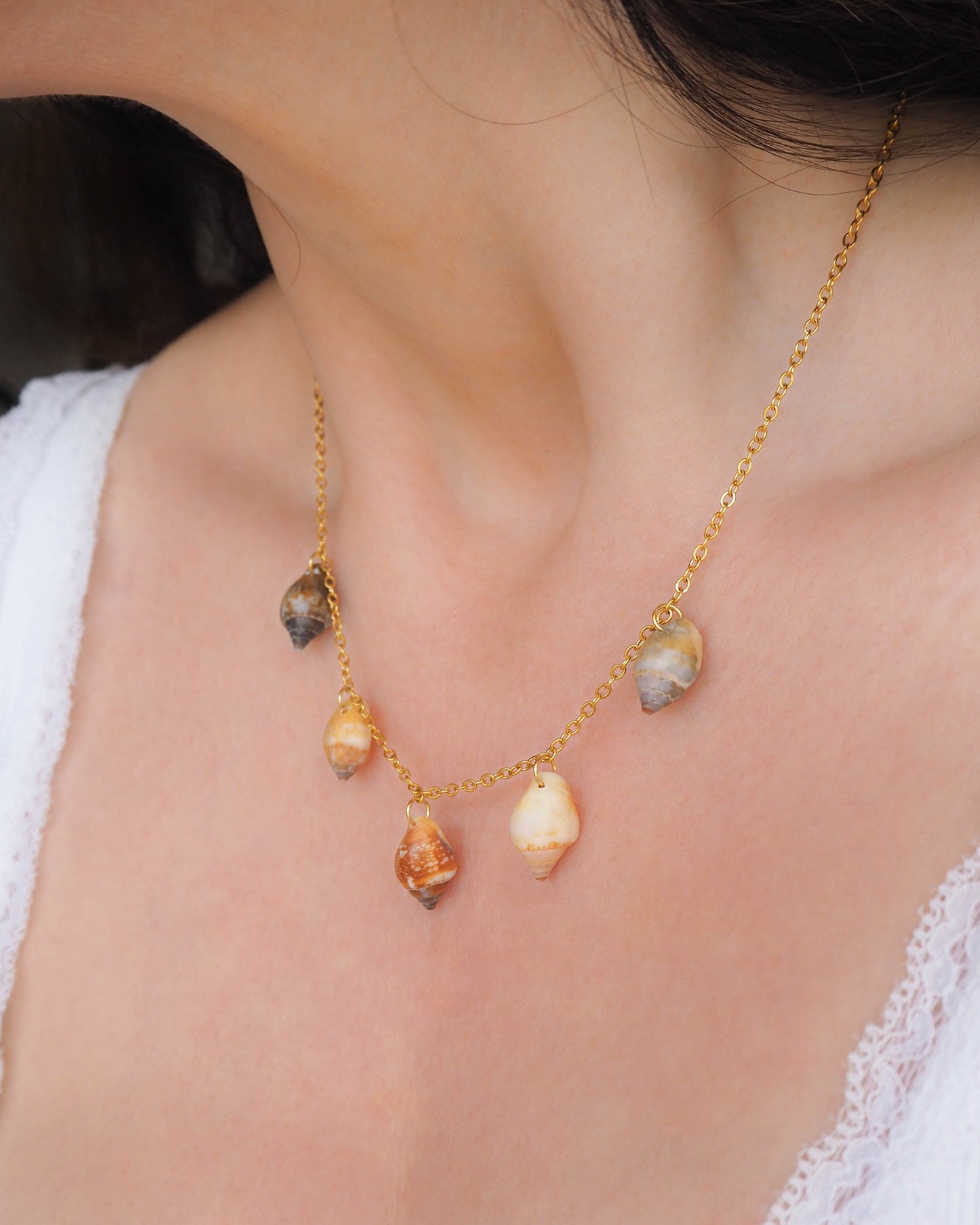 Model wearing Gold Charm Shell Necklace with 5 real shells from Algarve, Portugal. Seabylou Coastal Jewelry, Necklace with Real Shells