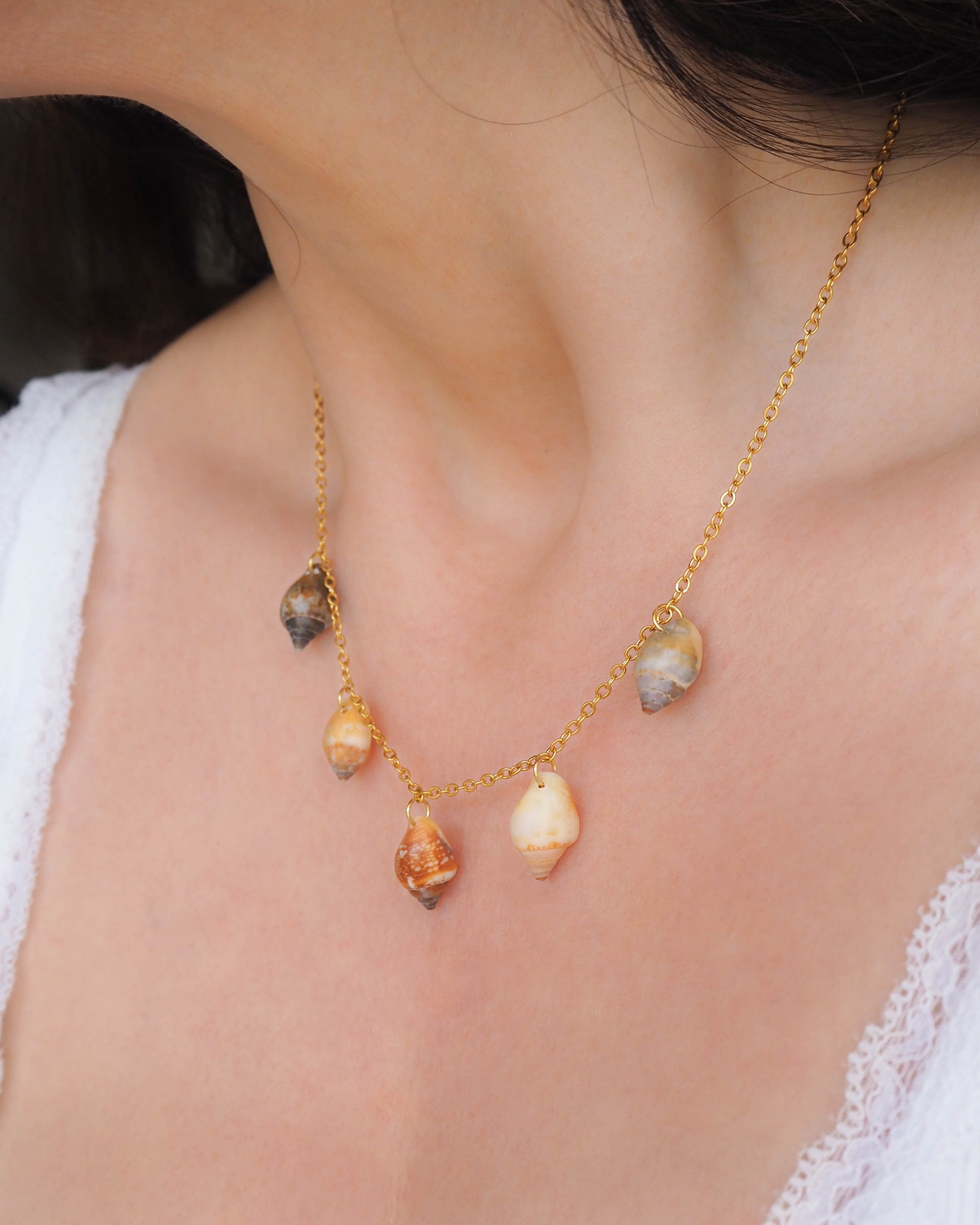 Model wearing Gold Charm Shell Necklace with 5 real shells from Algarve, Portugal. Seabylou Coastal Jewelry, Necklace with Real Shells