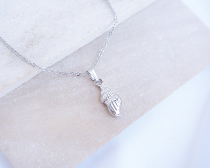 Silver Conch shell pendant necklace on a white marble surface