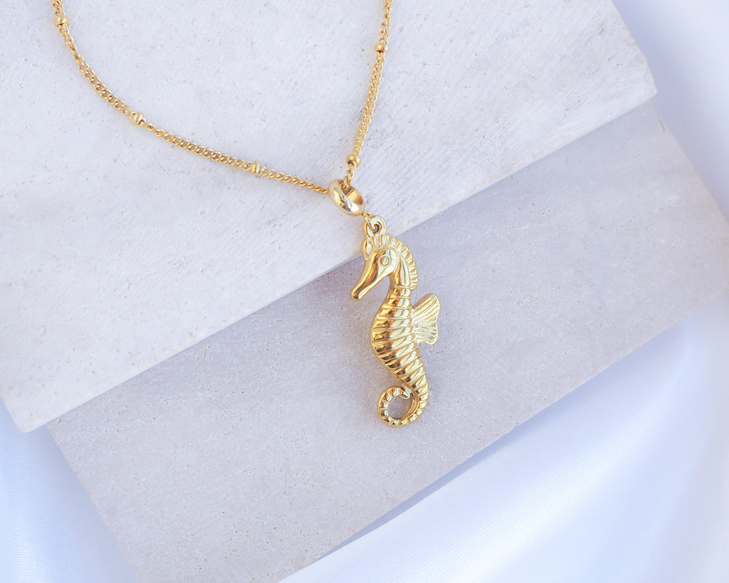 Close up of Gold Hippocampus Seahorse Necklace on stone displayed. Made with premium 18k gold stainless steel. Hippocampus pendant. Seahorse Jewelry, Sea by Lou, Seabylou