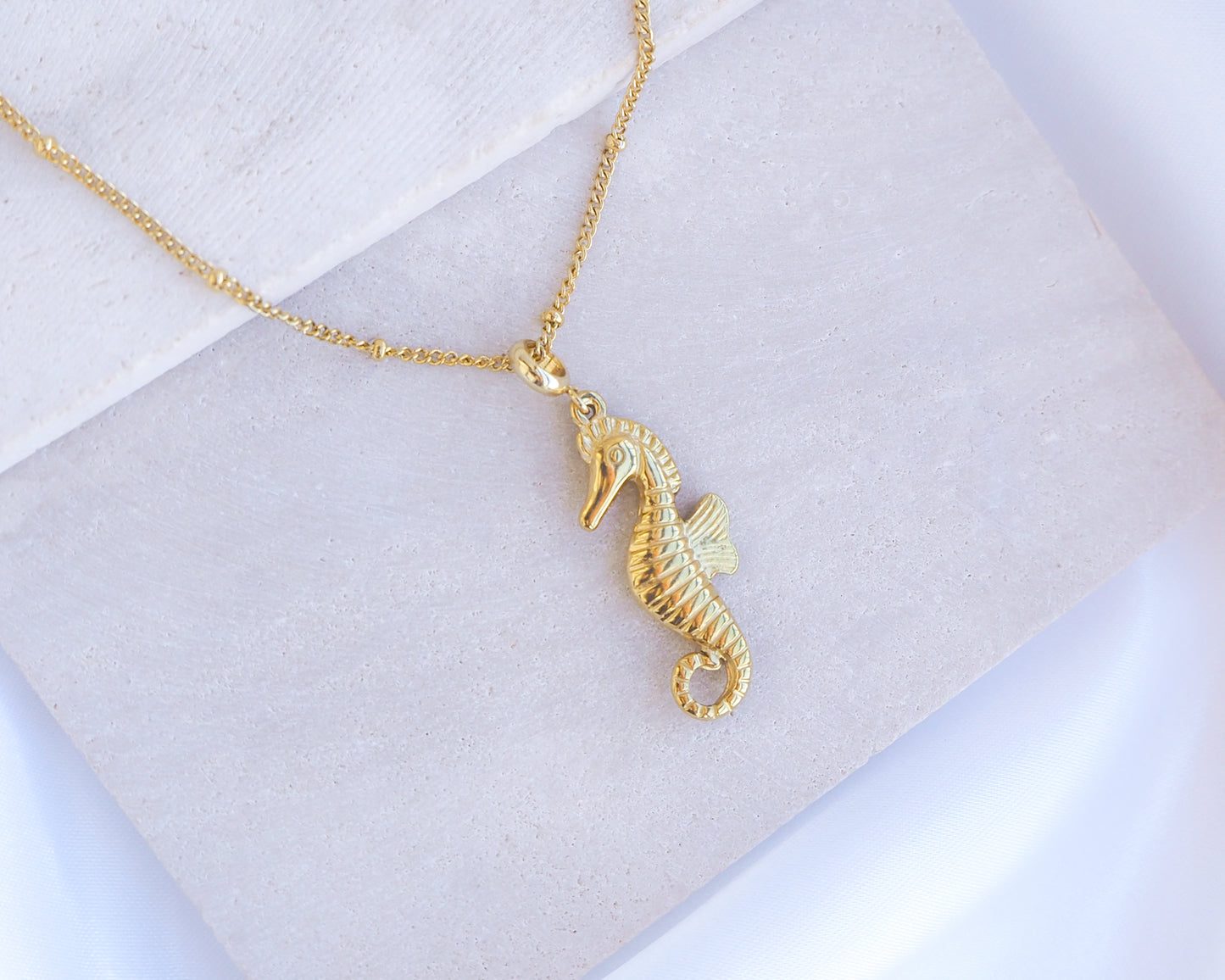 Gold Hippocampus Seahorse Necklace on stone displayed. Made with premium 18k gold stainless steel. Hippocampus pendant. Seahorse Jewelry, Sea by Lou, Seabylou