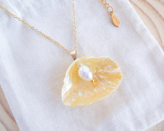 Soft Yellow Jingle Shell Gold Necklace on display, Mother of Pearl Pendant