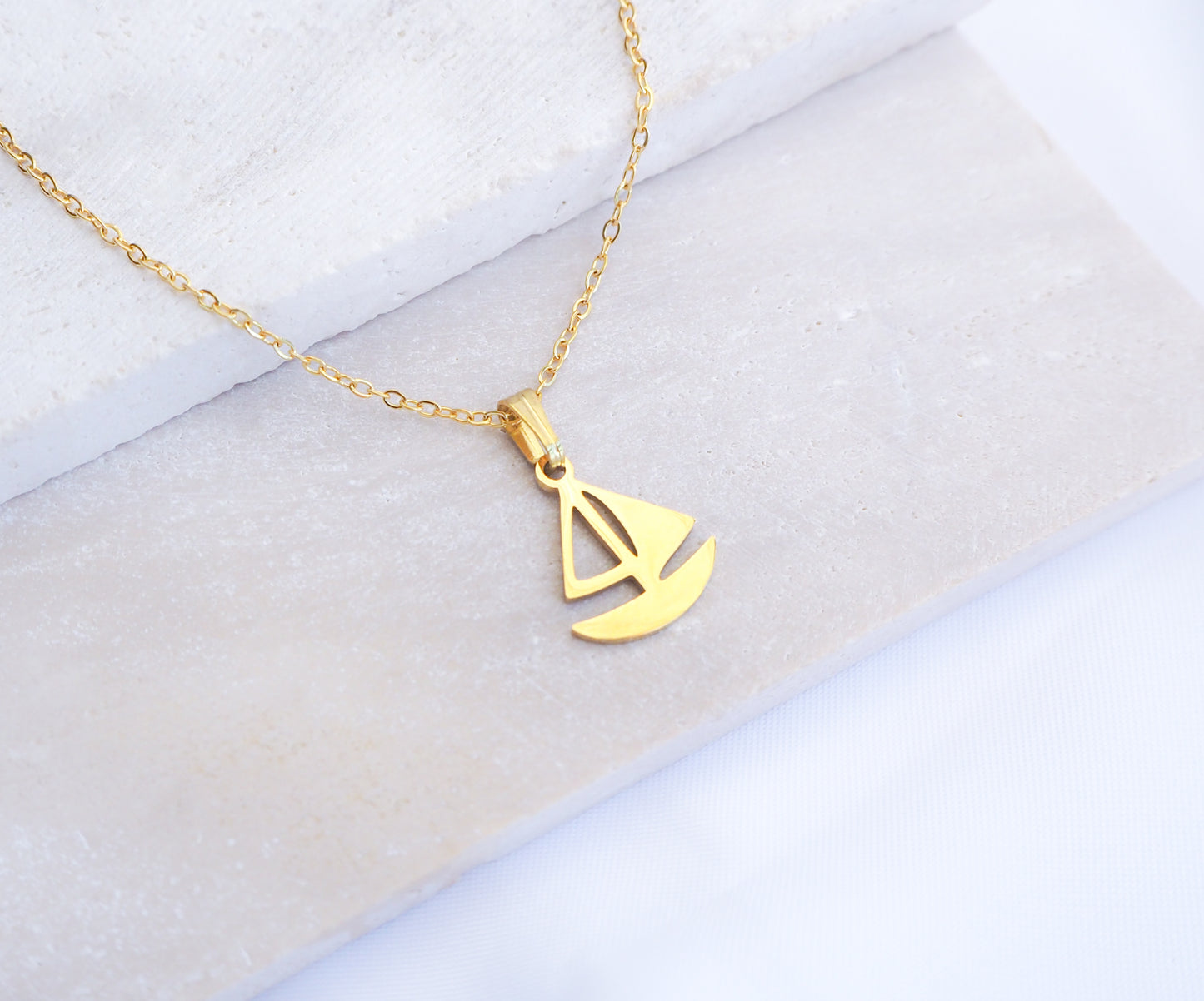 Gold Sailing Boat Necklace made with 14k gold stainless steel on display