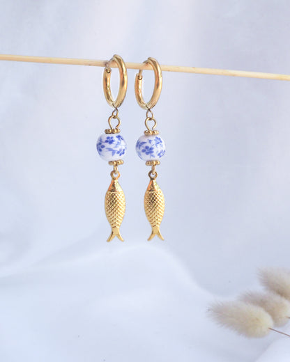 Gold fish-shaped earrings with blue floral beads on a light gray background. Gold Sardine Portuguese Ceramic Earrings