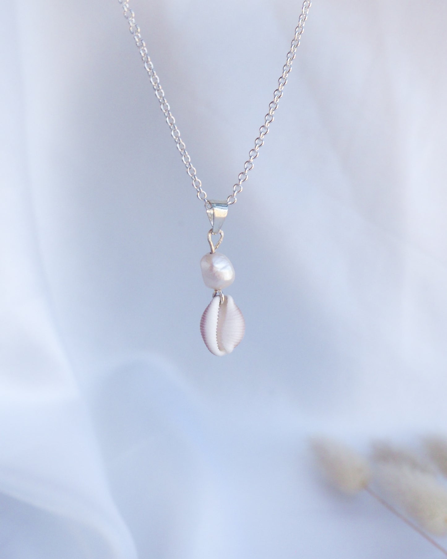 Silver necklace with a pendant on a light blue background. Silver Cowrie Shell Pearl wedding Necklace White Pearl  