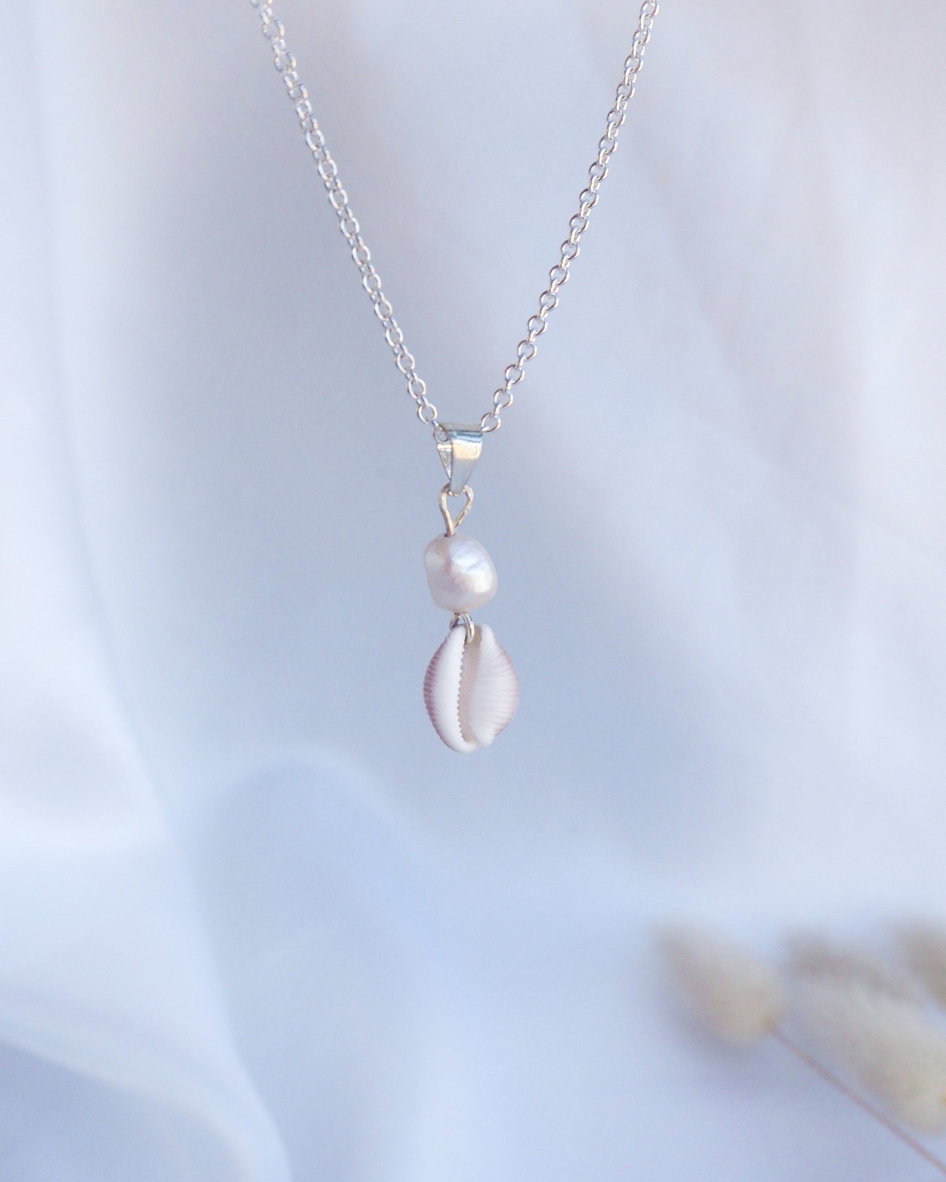 Silver necklace with a pendant on a light blue background. Silver Cowrie Shell Pearl wedding Necklace White Pearl  