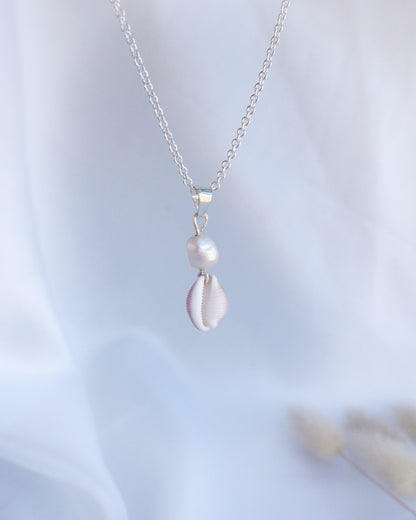 Silver necklace with a pendant on a light blue background. Silver Cowrie Shell Pearl wedding Necklace White Pearl  