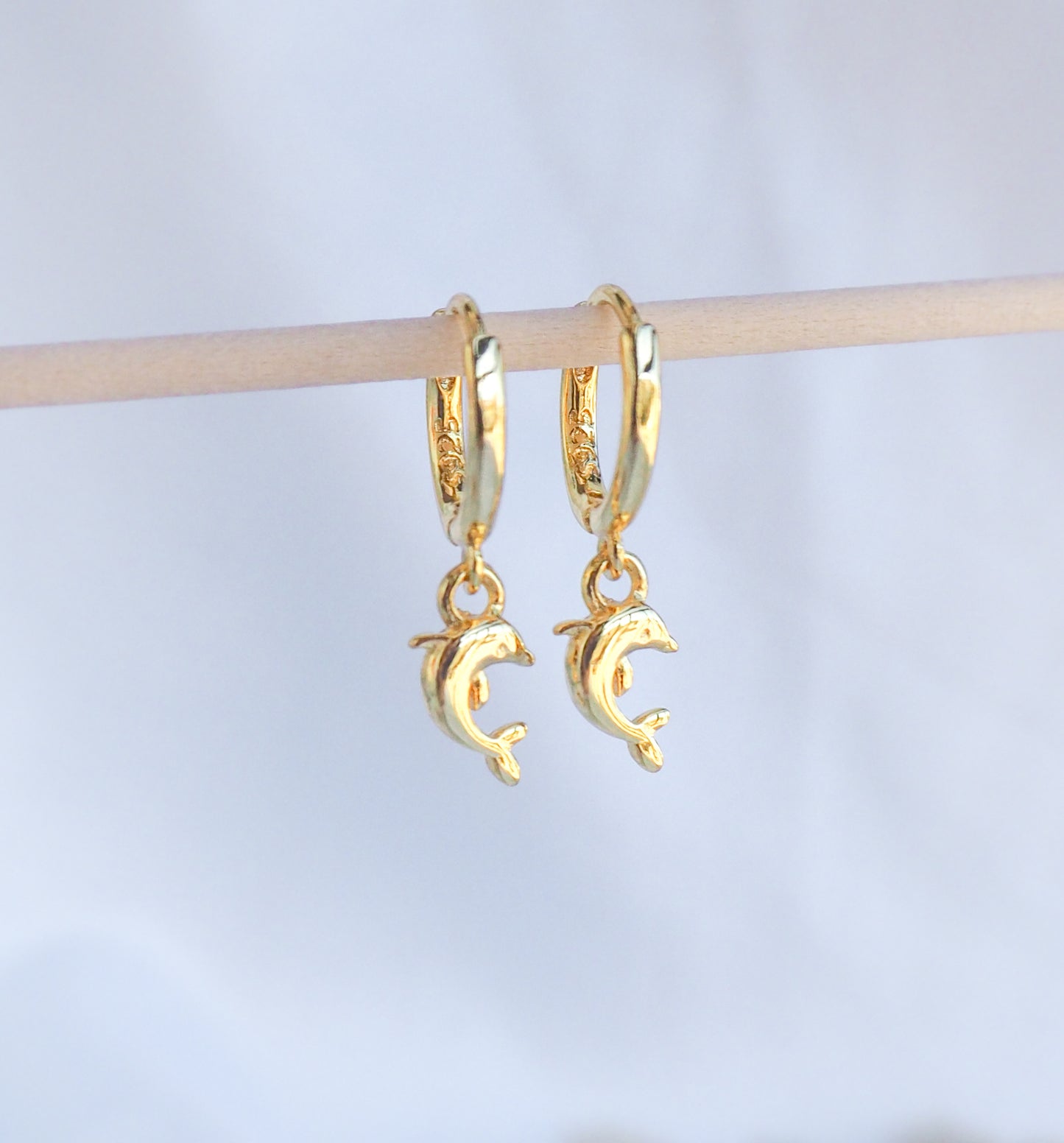 Front view of Gold Dolphin Earrings. Tiny dolphin pendants hoop earrings made of 14k gold vermeil 925 sterling silver