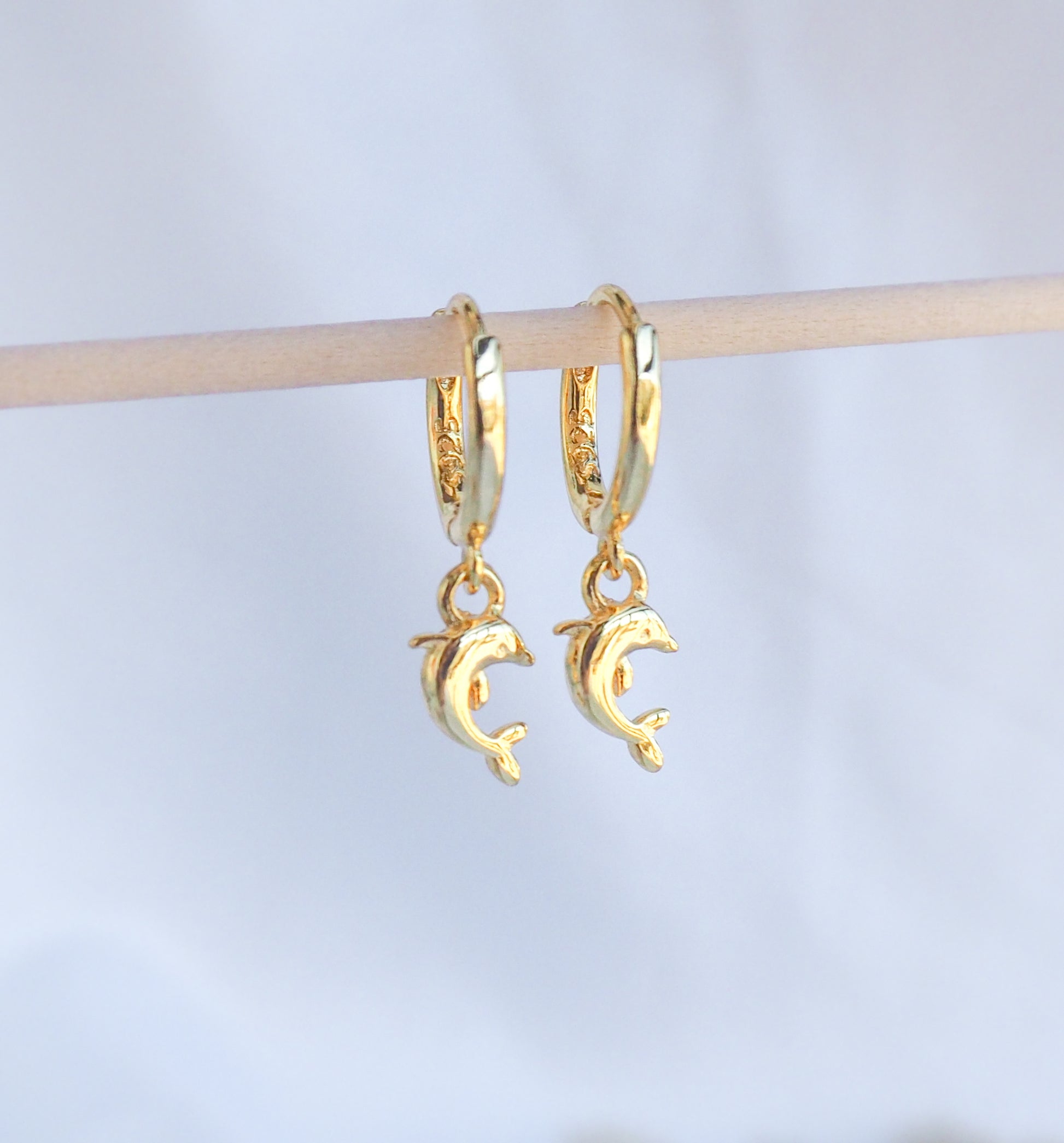 Front view of Gold Dolphin Earrings. Tiny dolphin pendants hoop earrings made of 14k gold vermeil 925 sterling silver