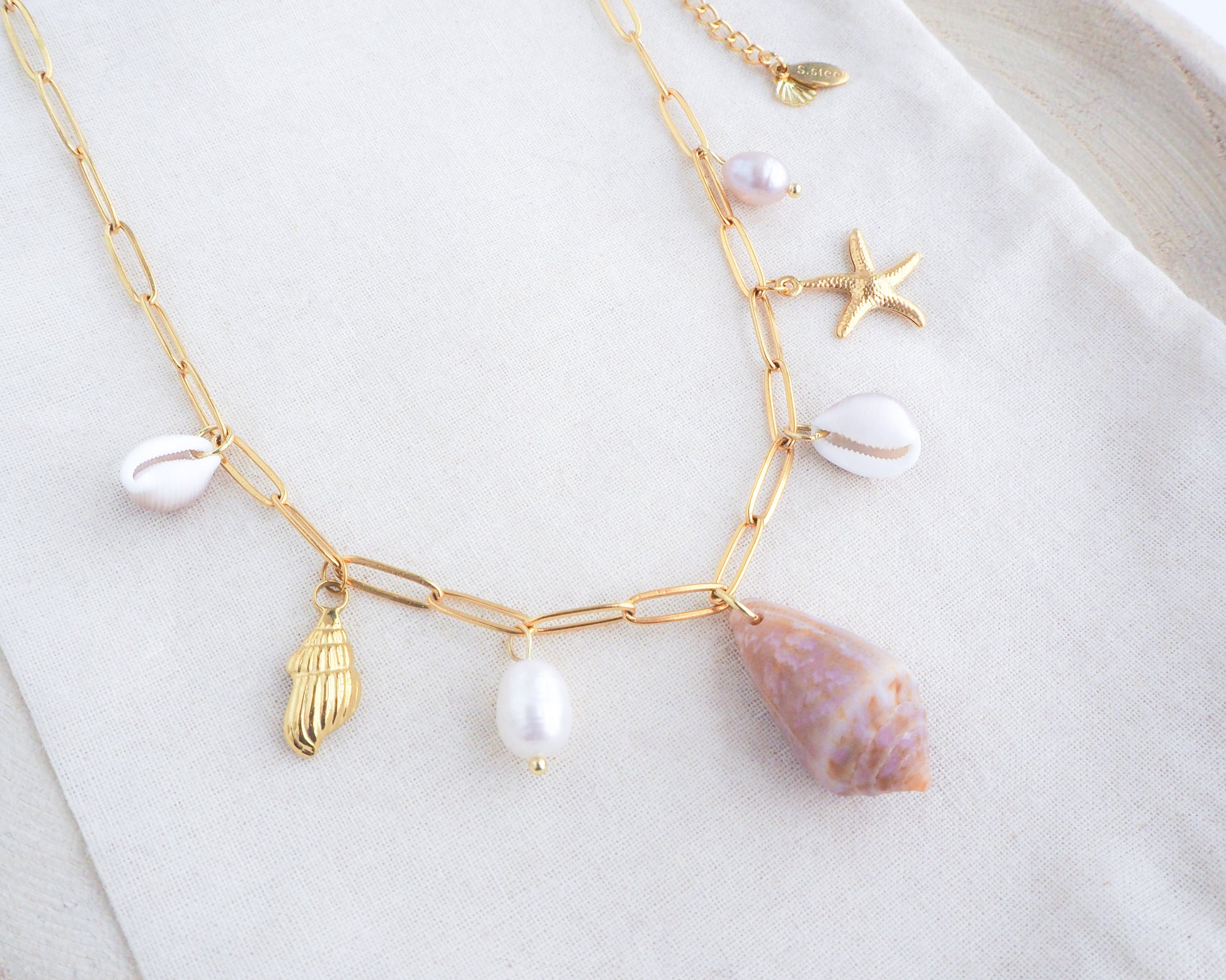 Gold Ocean Shell Charm Necklace on display, with cone and cowrie shells, freshwater pearls, starfish sea star shell pendants. 