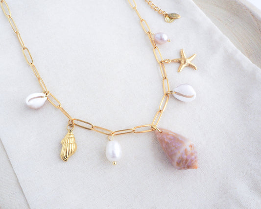 Gold Ocean Shell Charm Necklace on display, with cone and cowrie shells, freshwater pearls, starfish sea star shell pendants. 