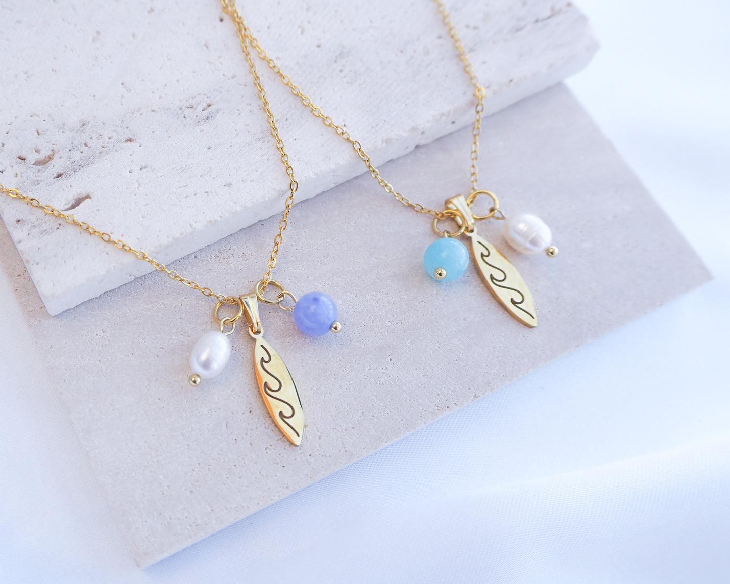 Gold surfboard pendant with freshwater pearl and gemstone beads. Made with premium 18k gold stainless steel. The gemstones are aqumarine and blue angelite. 