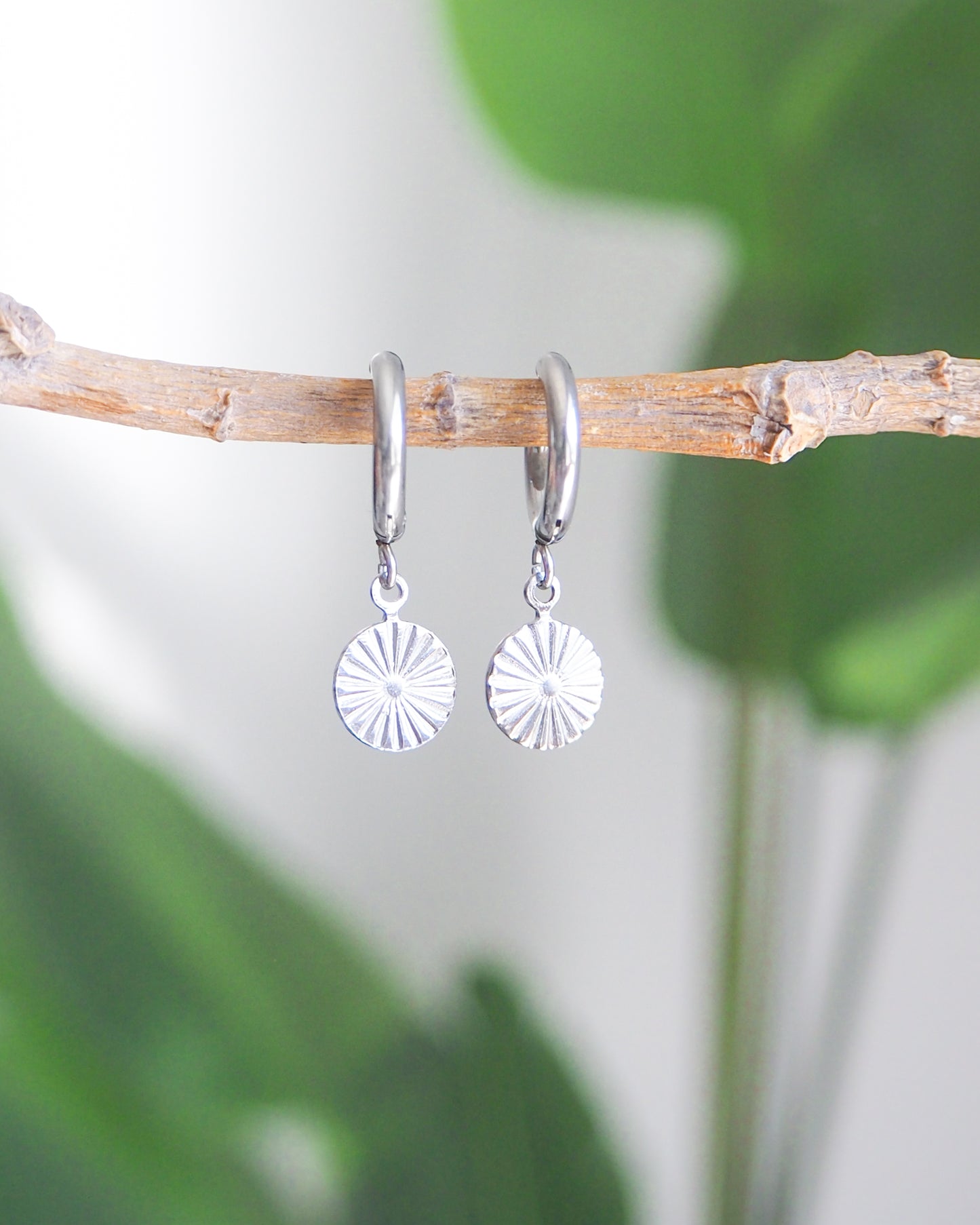 Silver Sunrise Hoop Earrings with green plant background. Made with 18k gold stainless steel hoops and tiny sun pendants. Beach Summer Jewelry 